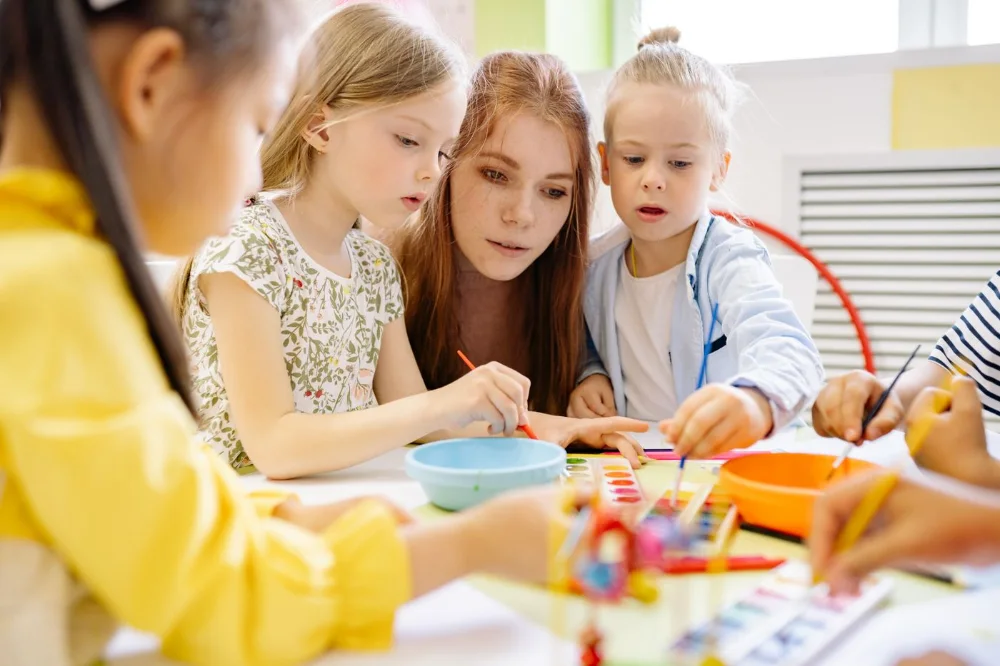 Educatrice guida un laboratorio creativo con un gruppo di bambini