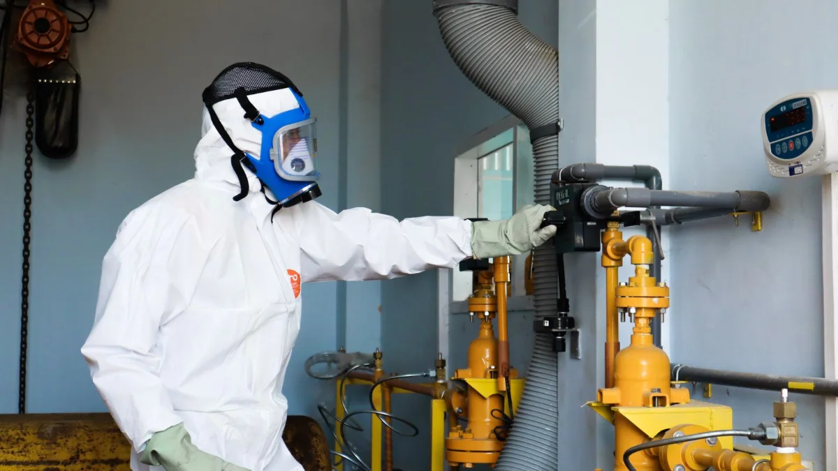 Tecnico con dispositivi di protezione accanto a un impianto automatizzato